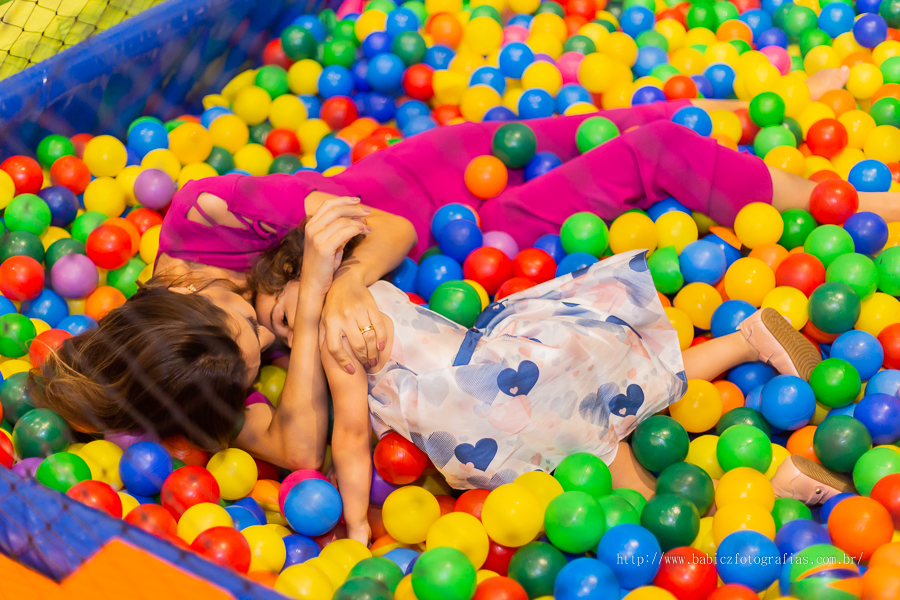 Fotografia da aniversariante brincando com a mamae na piscina de bolinha