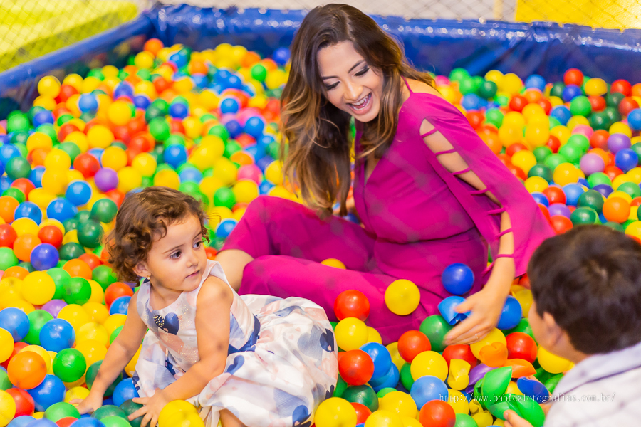 Fotografia da aniversariante brincando com a mamae na piscina de bolinha