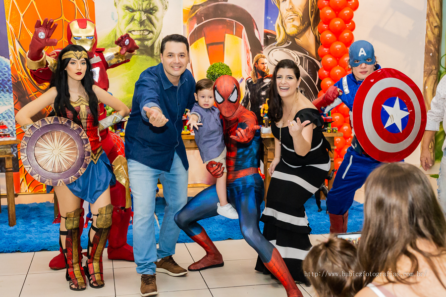 Fotografia do aniversariante Théo com os pais junto com os personagens da liga da justiça e vingadores no buffet em Maringá. 
