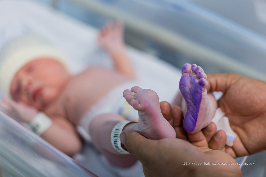Fotografia do nascimento parto do Samuel na Maternidade Santa Casa Maringá. Pela fotografa Rose Babicz. Apos o nascimento podemos ver o bebe com tinta azul no pezinho lembrando o formato de coração.