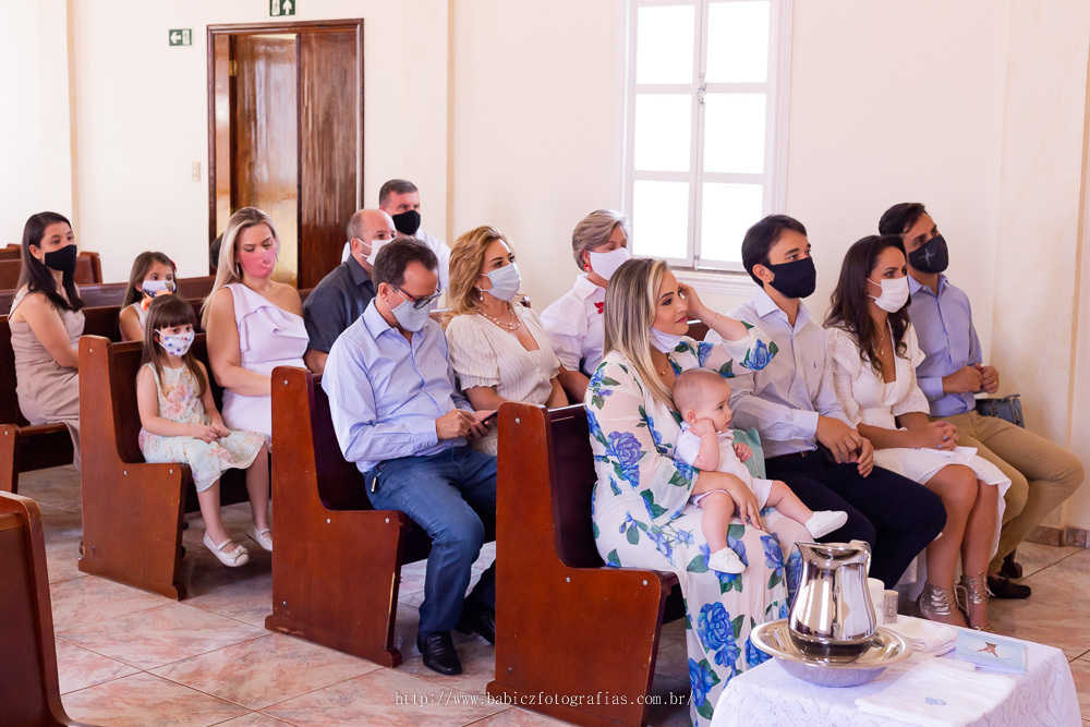 Fotografia da familia sentada nos banco da capela madre paulina no dia do batizado do Arthur