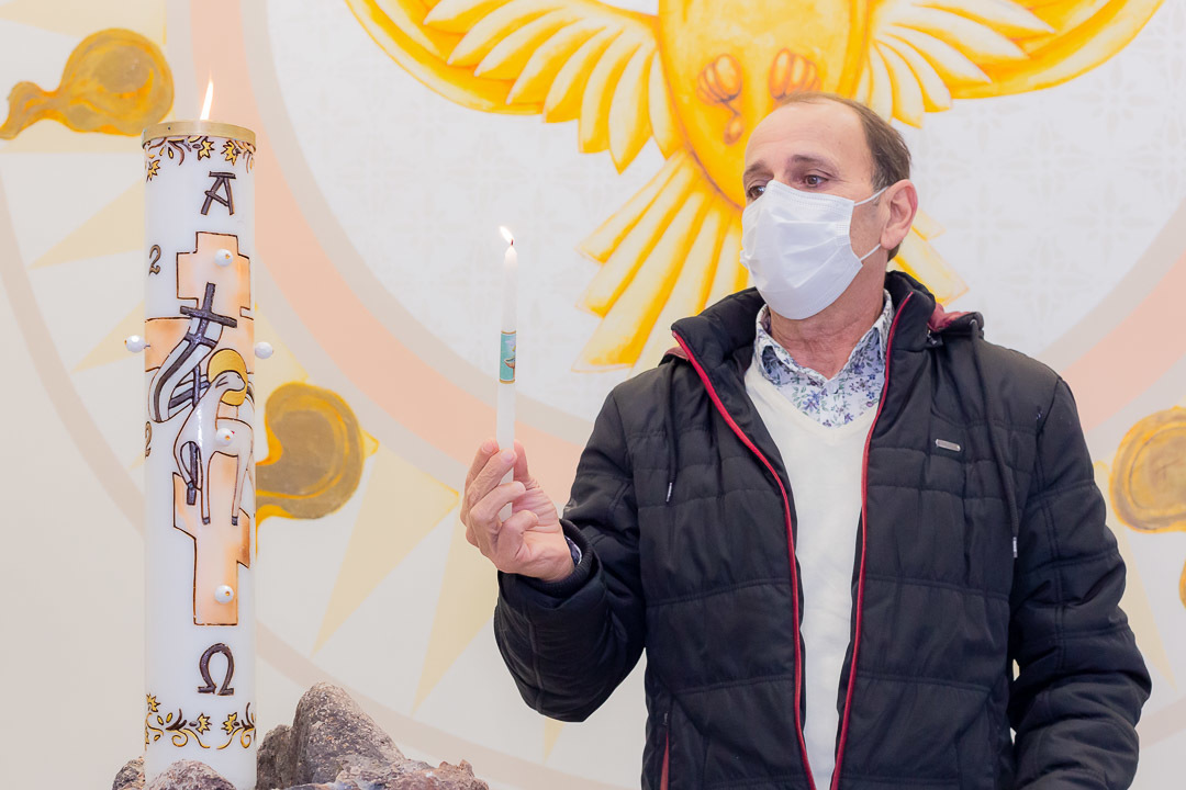 Foto momento em que padrinho acende a vela em um batizado na igreja católica - Símbolo do batismo