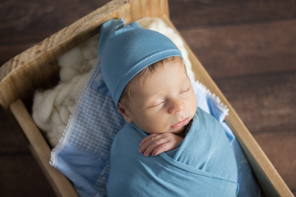 ensaio recém nascido com bebê enrolado no wrap e dormindo no berço