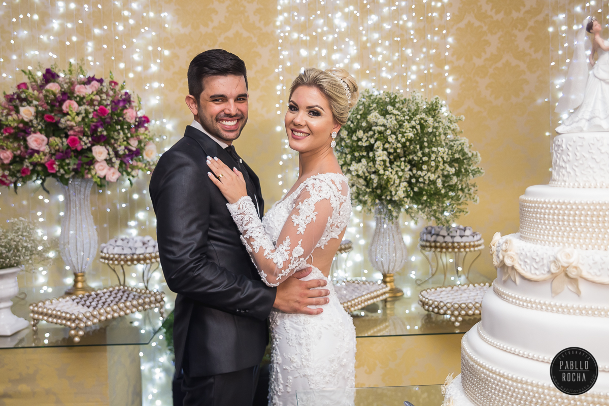 noivos passando para fotos na mesa do bolo