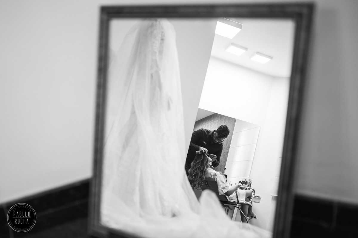 noiva se aprontando com vestido de noiva ao fundo