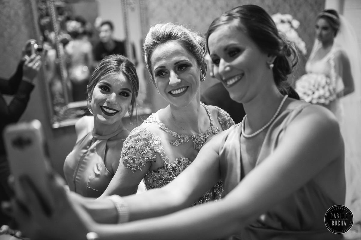 madrinhas fazendo self com noiva ao fundo