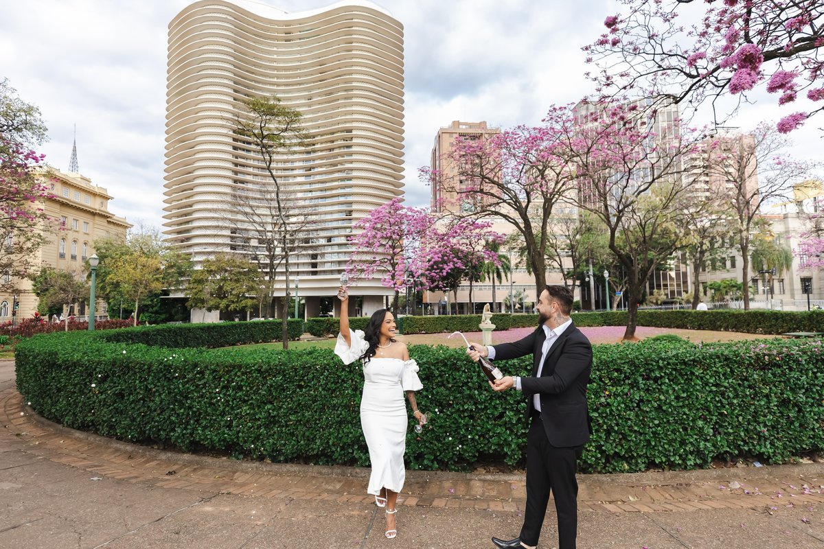 Nathalia e Enrico brindando com espumante na Praça da Liberdade