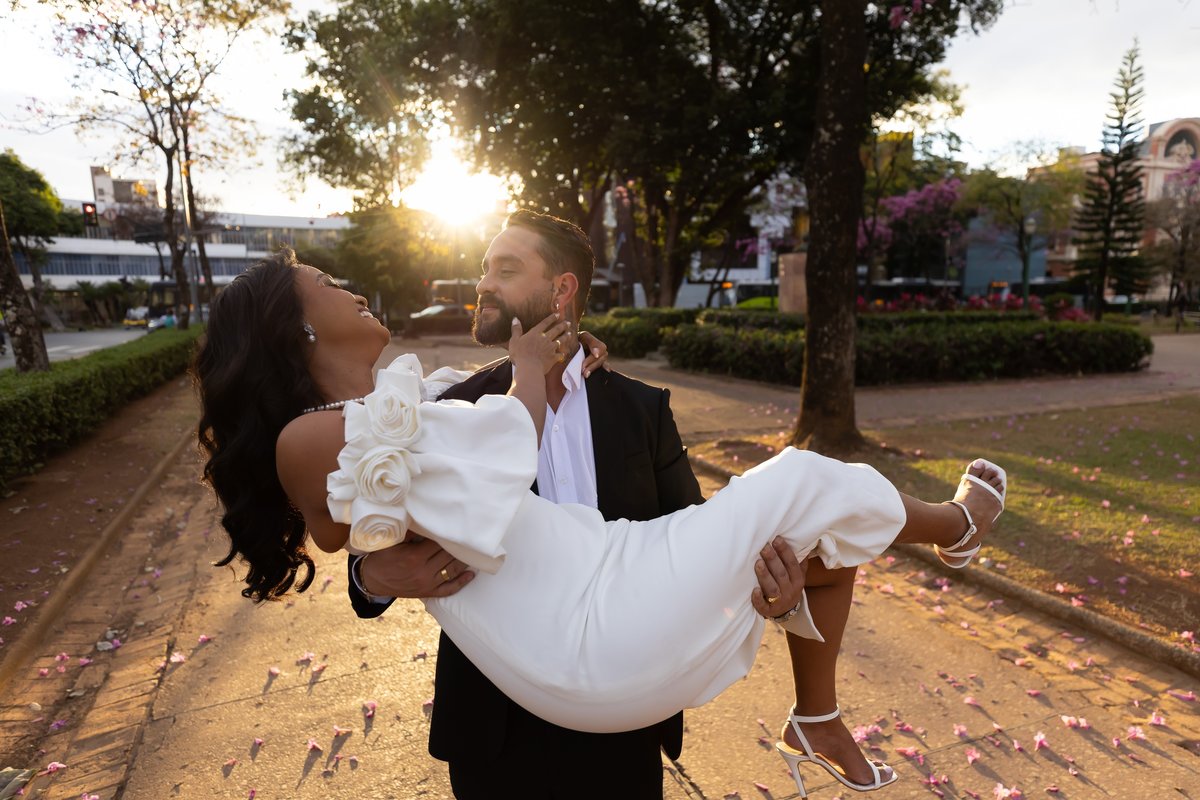 Noivo erguendo a noiva ao entardecer na Praça da Liberdade