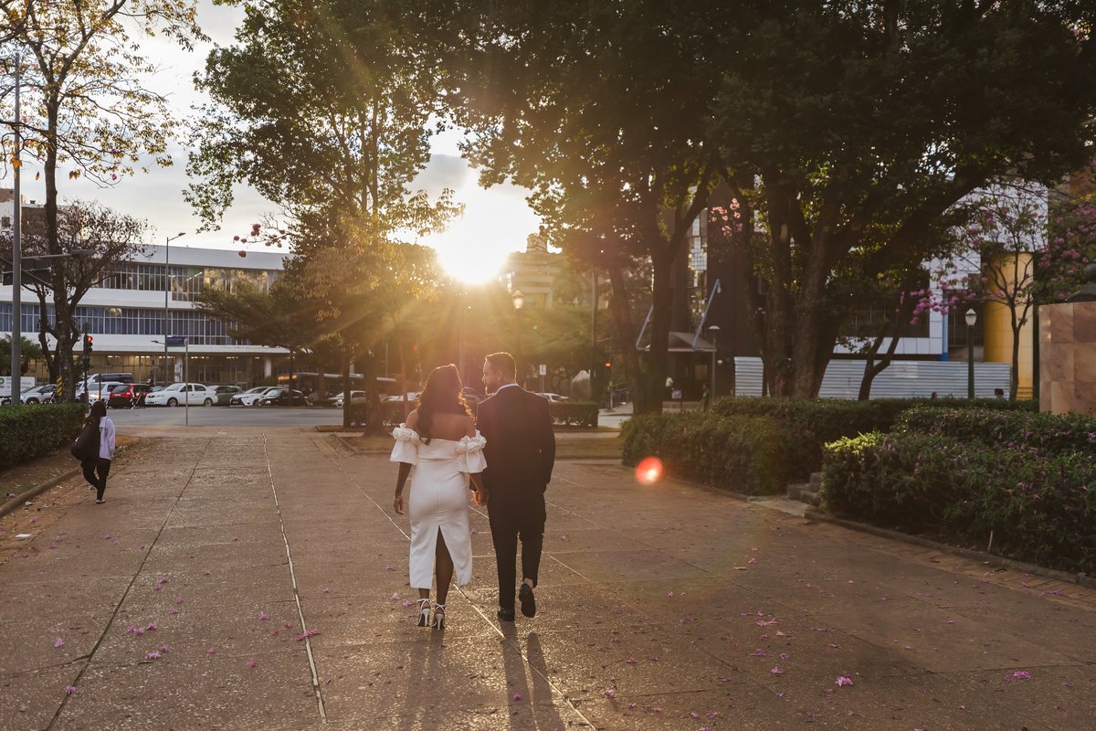 Casal caminhando ao entardecer com o sol entre as árvores