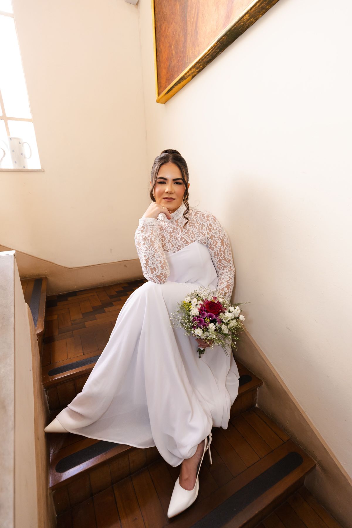 Noiva com vestido de gola alta em renda na escada da Casa Belloni