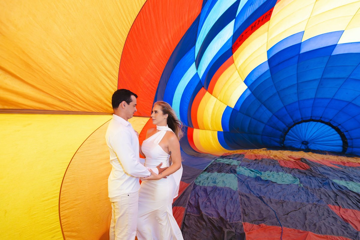 Casal noivo e noiva vestidos de branco no ensaio de balão de ar quente