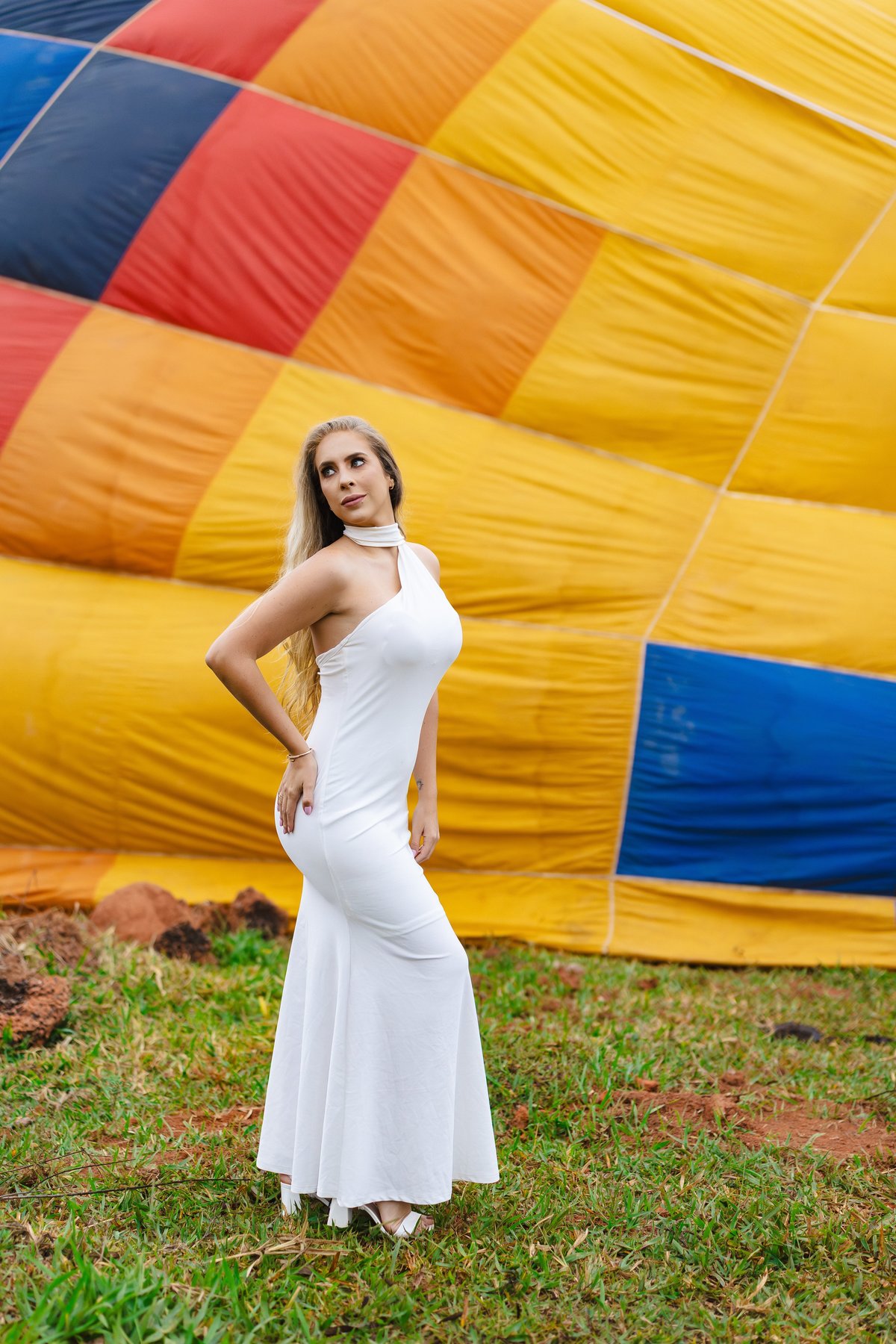 Noiva de vestido branco de pé junto ao balão de ar quente inflando