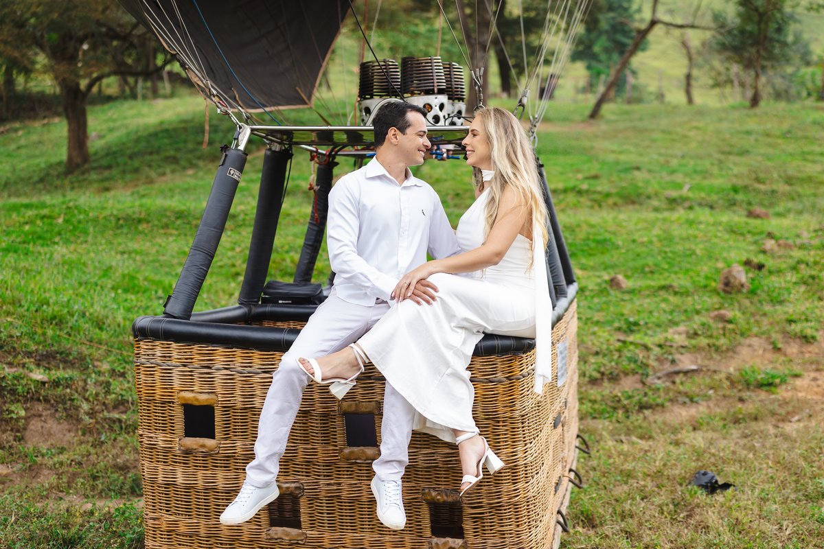 Casal sentado na borda do cesto de balão em ensaio pré-casamento