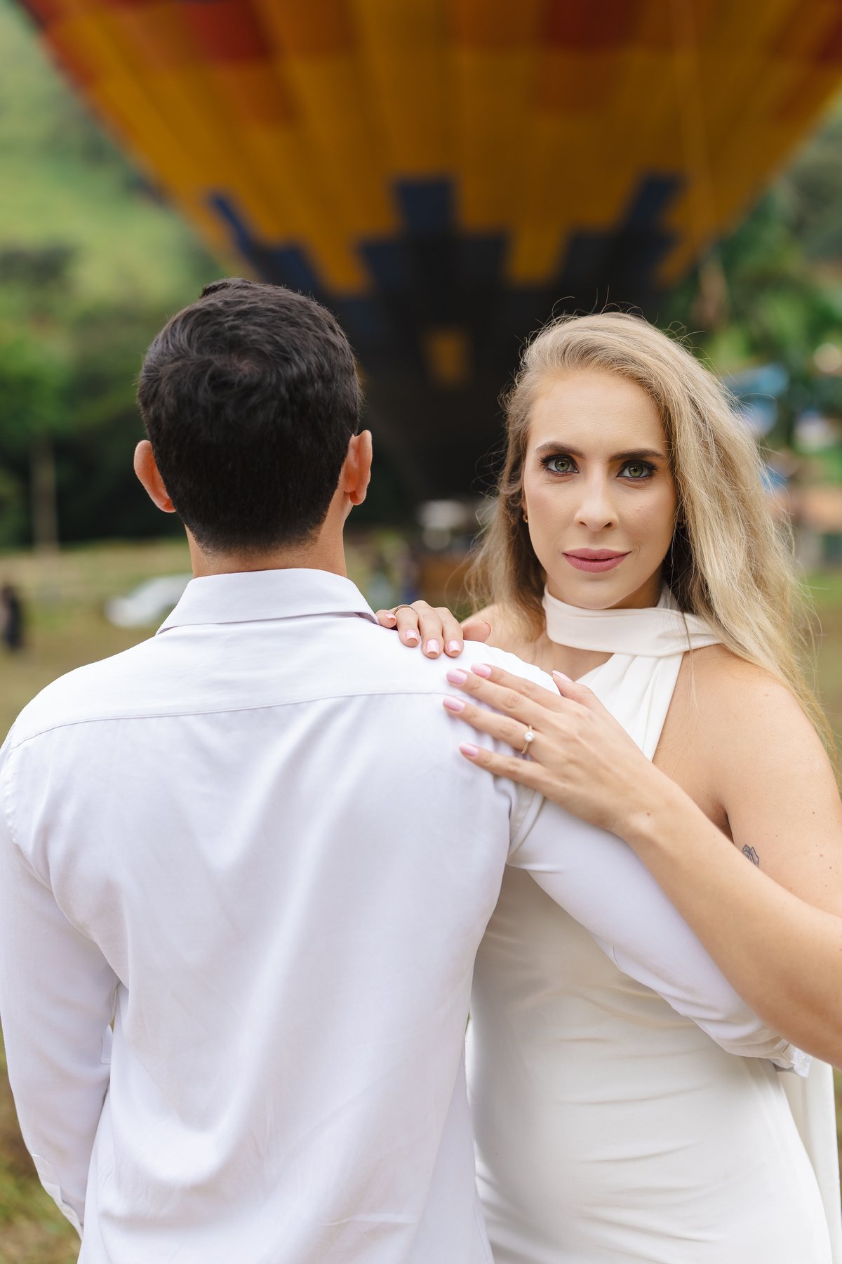 Noiva com a mão no ombro do noivo em retrato de ensaio pré-wedding