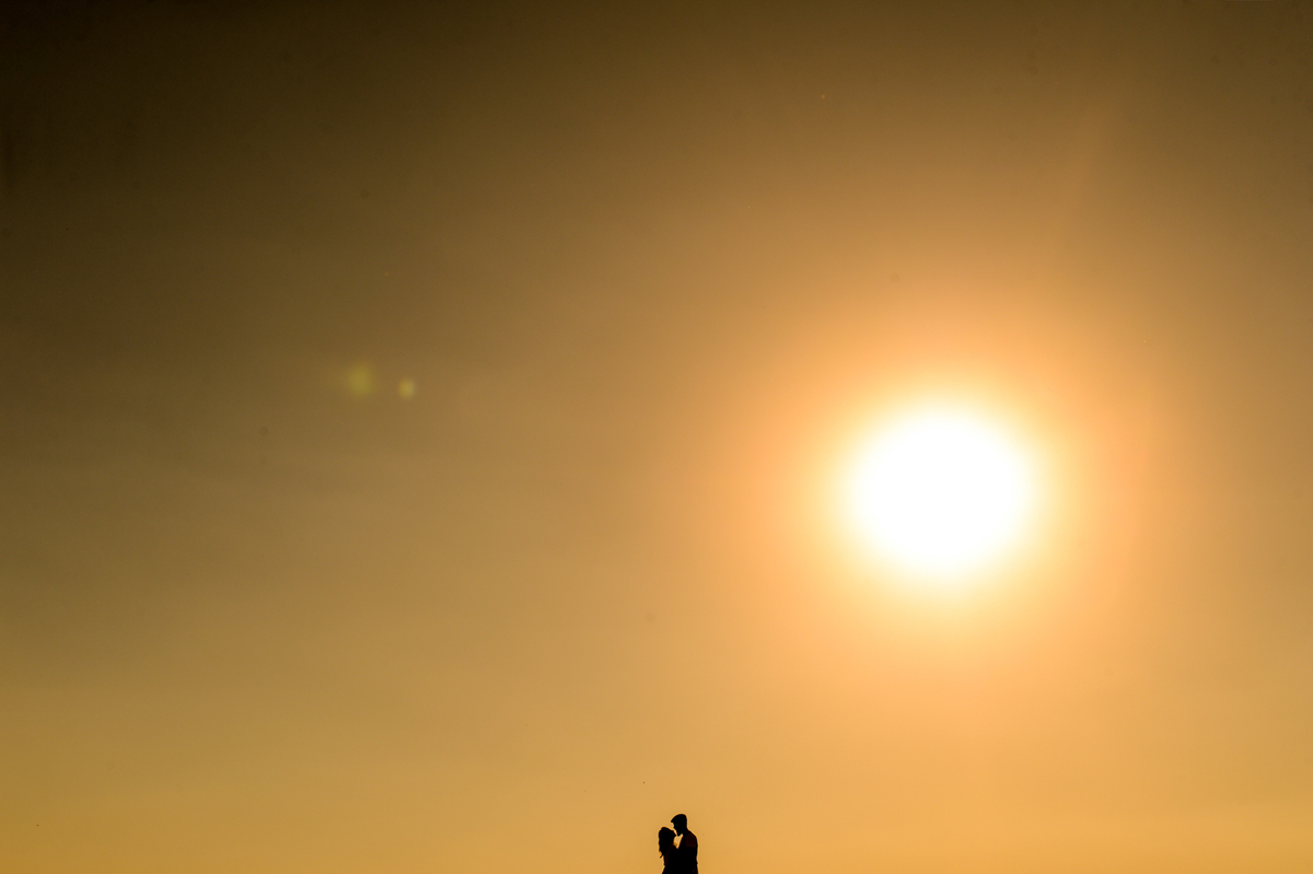 ensaio do casal pre-wedding noiva e noivo se beijando o horizonte com o sol de fundo somente silhueta do casal foto minimalista  feita em Holambra cidade das flores 
