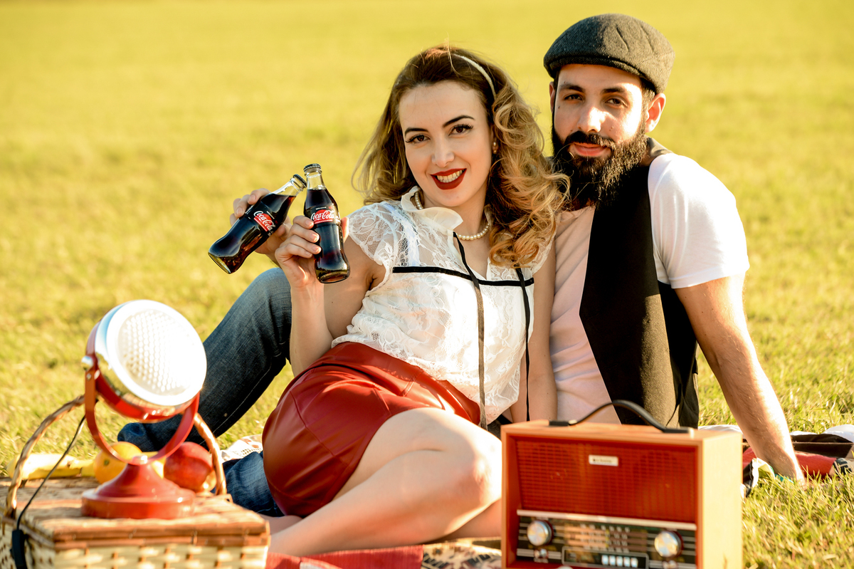 ensaio retro casal com estilo unico com coisas antigas no cenário como radio antigo garrafa de coca-cola com um gramado verde feito na plantação de feno em Holambra cidade das flores 