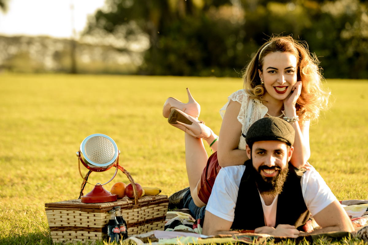 ensaio retro casal com estilo unico com coisas antigas no cenário como radio antigo garrafa de coca-cola com um gramado verde feito na plantação de feno em Holambra cidade das flores 