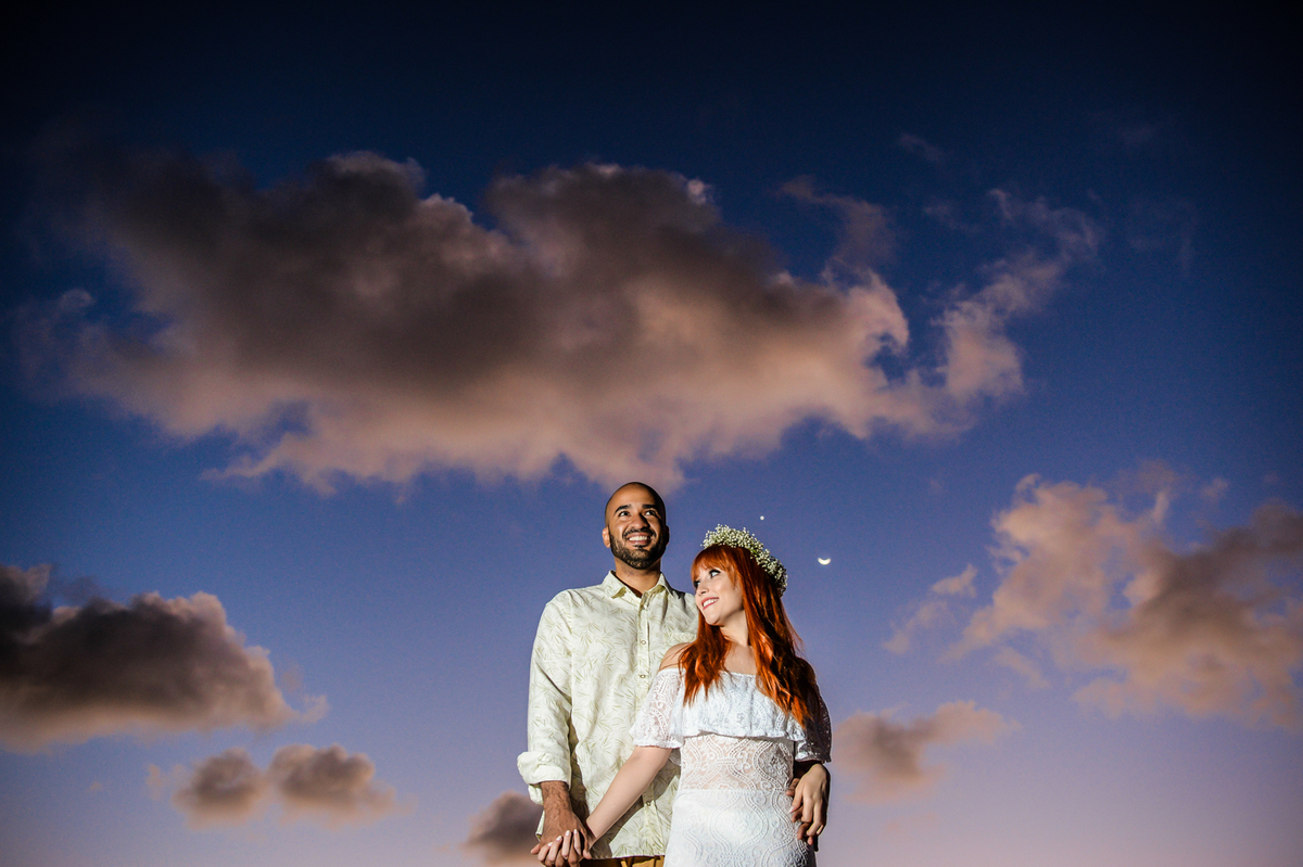 casal juntos com a lua aparendo ao fundo momento do nascer do sol na praia 