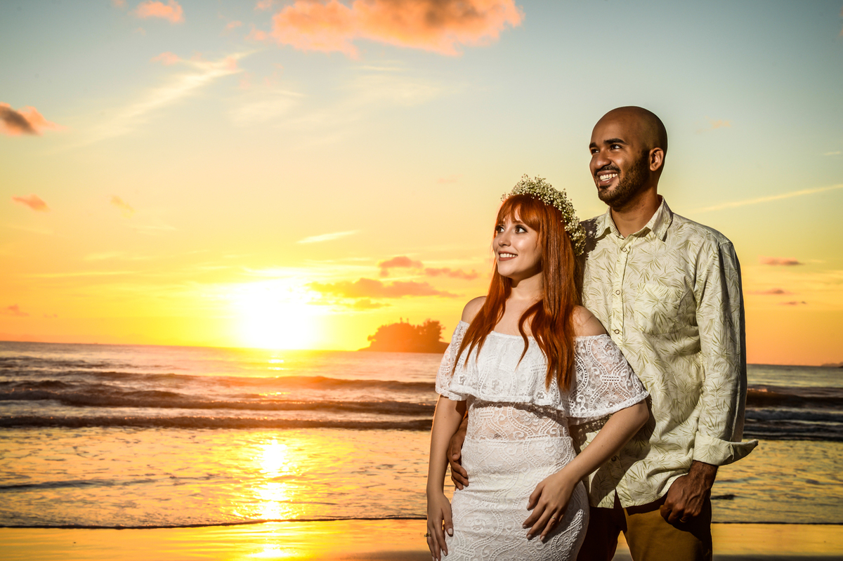 com o sol nascendo na praia ao fundo do casal unido e apaixonado olhando para o futuro 