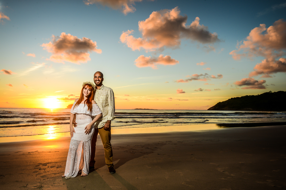 com o sol nascendo na praia ao fundo do casal unido e apaixonado 