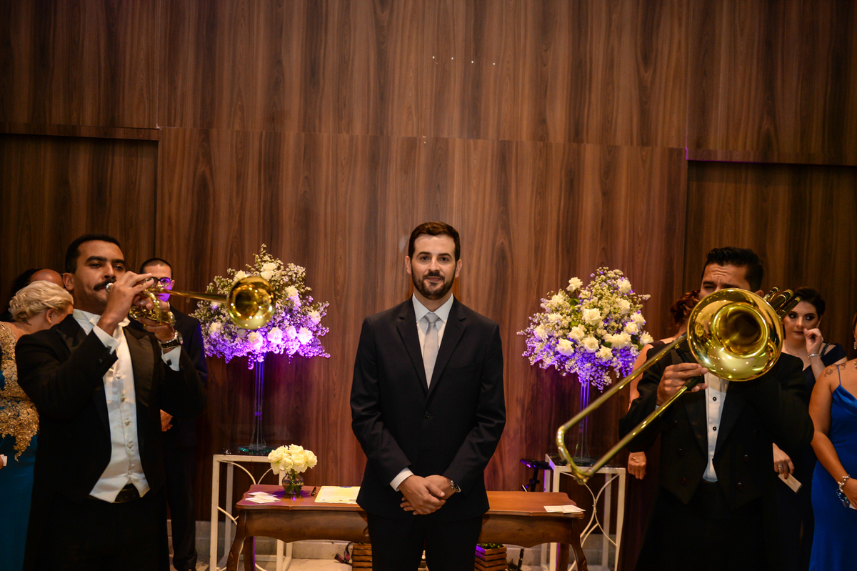 noivo no altar aguardando a noiva e os clarins tocando ao lado dele 