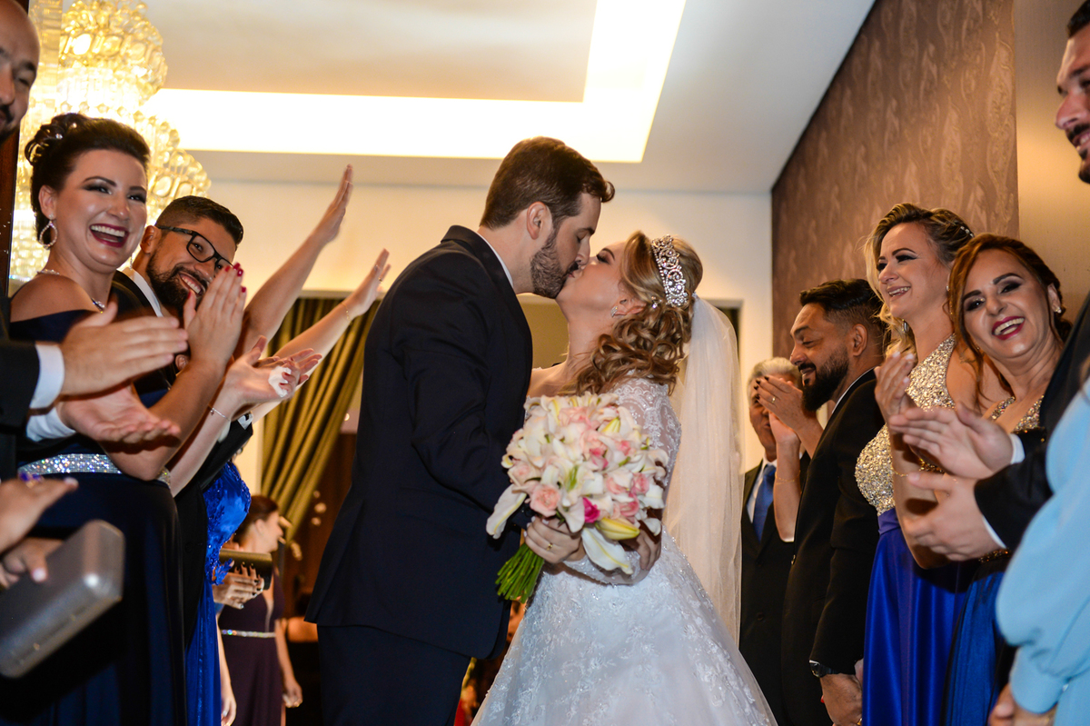 aquele beijo dos noivos na saida da cerimonia com todos os padrinhos ao lado apontando para eles 