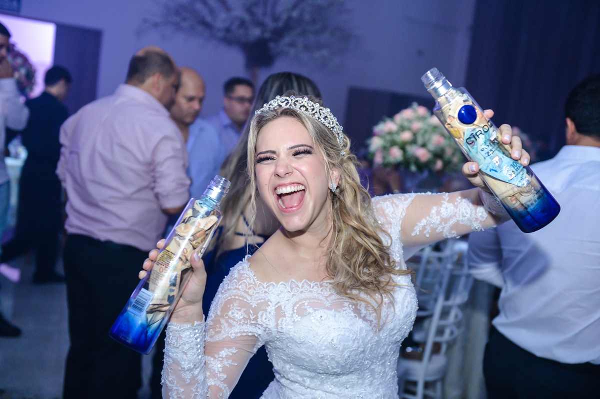 noiva segurando duas garrafas cheio de dinheiro do corte da gravata 