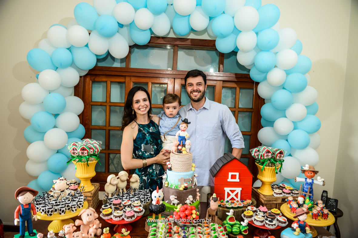 foto da familia juntos na mesa do bolo com muitos doces finos e balões ao fundo