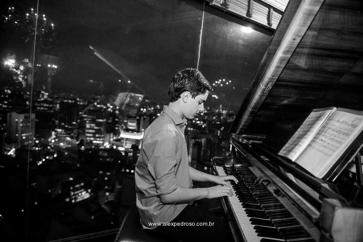 garoto tocando piano no restaurante Terraço Italia no predio circulo italiana com a vista de sao paulo a noite de fundo 