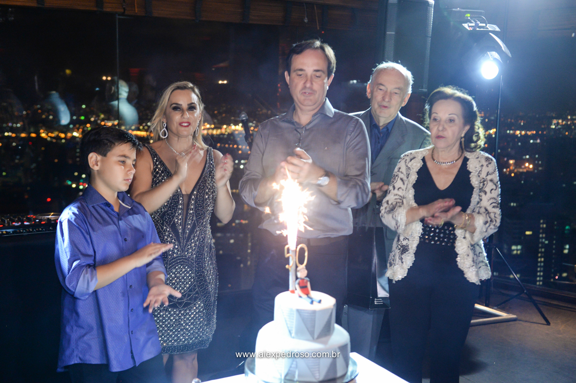 foto do aniversariante cantando parabens junto com a familia e um bolo com vela  restaurante Terraço Italia com a visão a noite da cidade de sao paulo que fico no predio circulo Italiano no centro de sao Paulo onde se tem a vista de sao paulo 