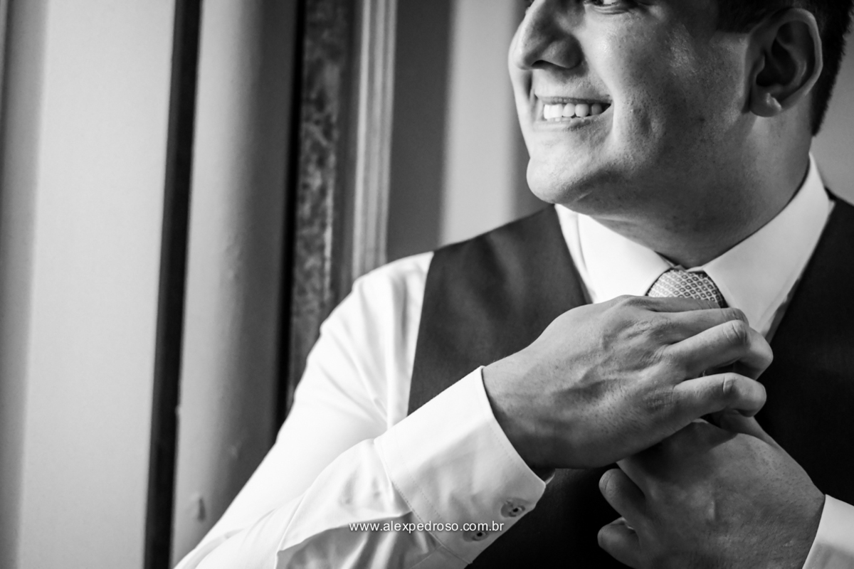 foto preto e branco do noivo arrumando a gravata momentos antes da chegada da noiva 