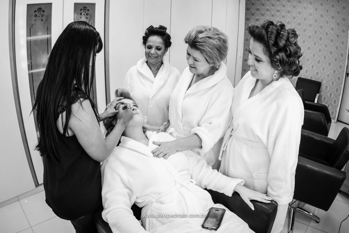 foto em Preto e Branco da noiva se maquiando junto com a mae e as irmas e a maquiadora maquiando 