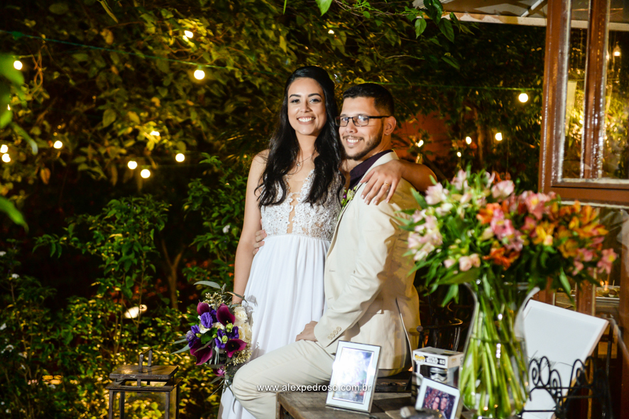 noiva junto com noivo sorridente proximo da mesa decorada no buffet flores na varanda com porta retrado com fotos do casal apaixonado 