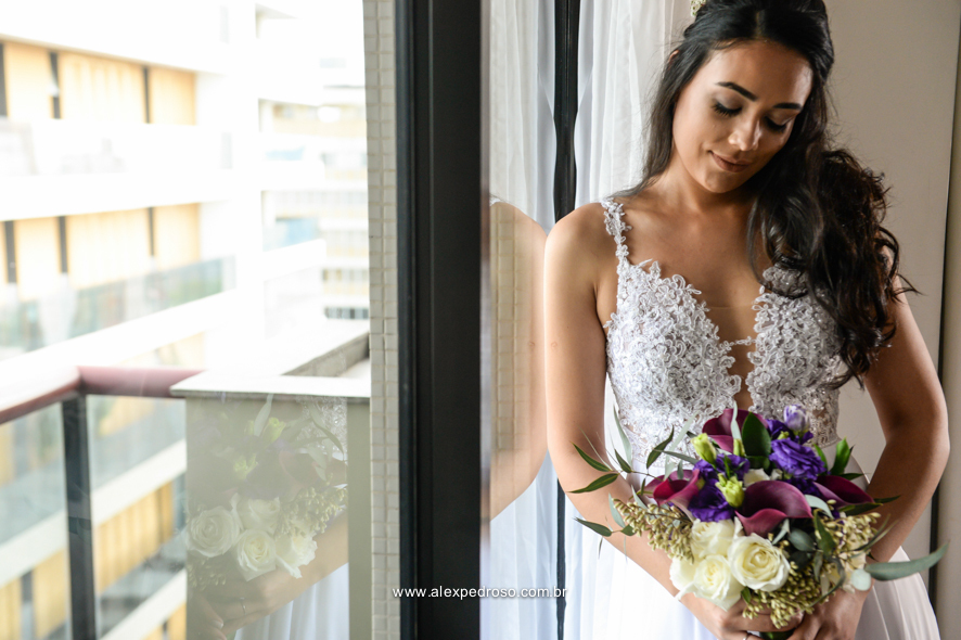 noiva ao lado da janela segurando o buque 