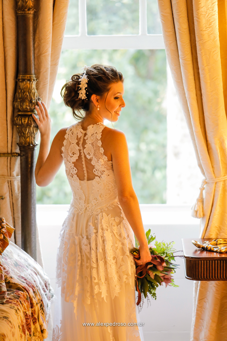 noiva com vestido e buque de flores na mao com uma janela de fundo