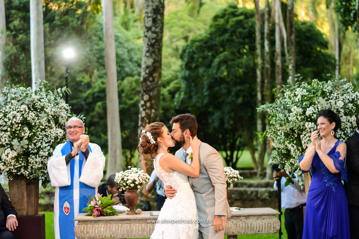foto preto e branco do momento do beijo do casal com o celebrando ao lado e a mae aplaudindo