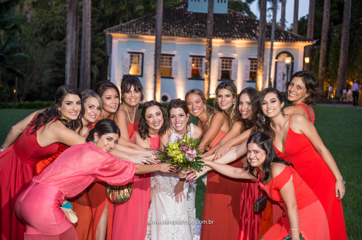 foto da madrinhas todas juntas de vestidos vermelho segurando o bique da noiva