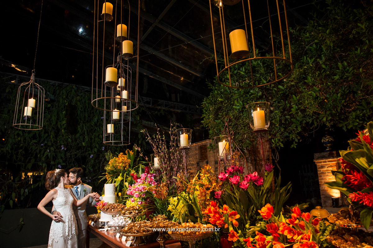 noivos juntos cortando o bolo com uma mesa toda decorada com flores doces finos e velas suspensas