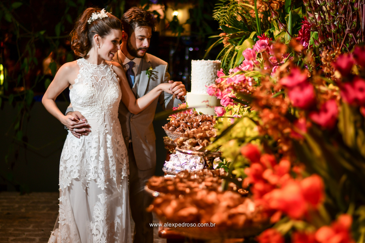 noivos juntos cortando o bolo com uma mesa toda decorada com flores doces finos e velas suspensas