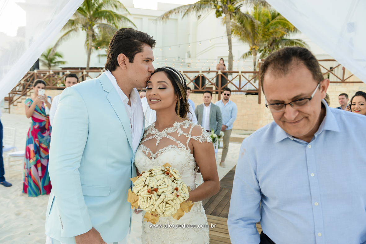noivo vestindo Ricardo Almeida recebendo a noiva com um beijo na testa e seu pai passando ao lado em direção do altar no Mandala Beach Club 