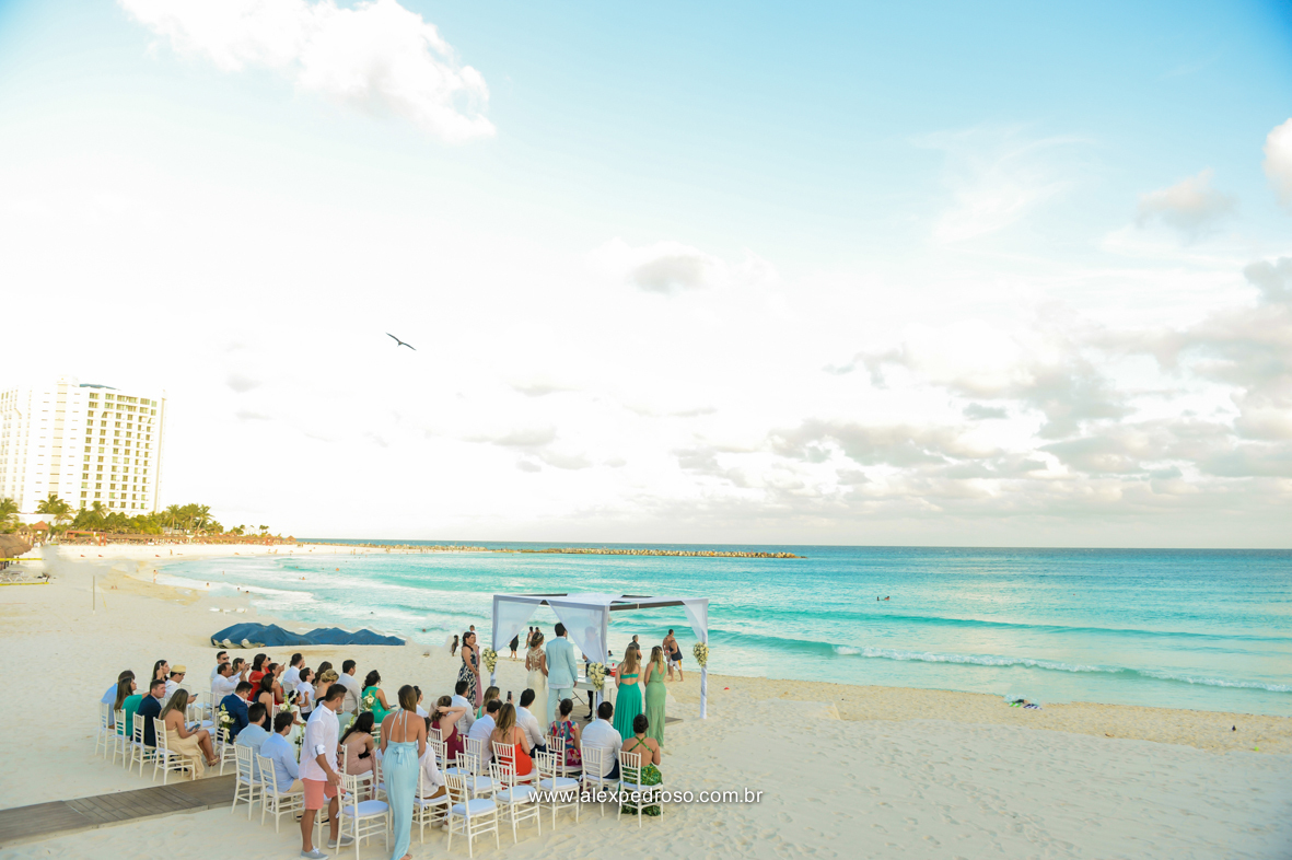  cheia de convidados e os noivos no altar fotos do local da cerimonia pe na areia com as cadeiras e o altar mais al fundo com o mar e ceu azul feito no Mandala Beach Club