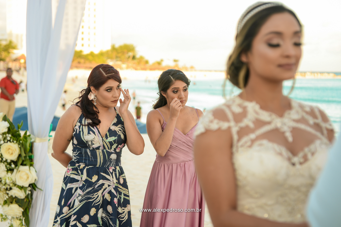 noiva emocionada na cerimonia e duas madrinhas ao fundo chorando de emoção 