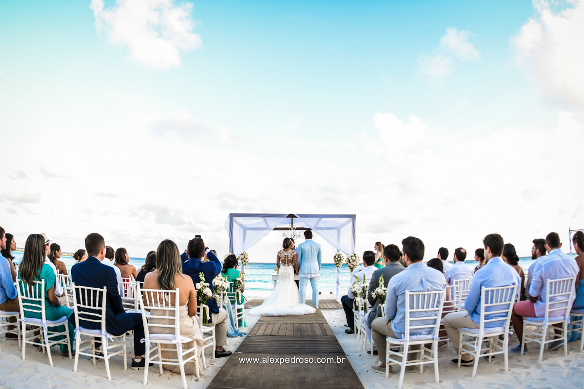  cheia de convidados e os noivos no altar fotos do local da cerimonia pe na areia com as cadeiras e o altar mais al fundo com o mar e ceu azul feito no Mandala Beach Club