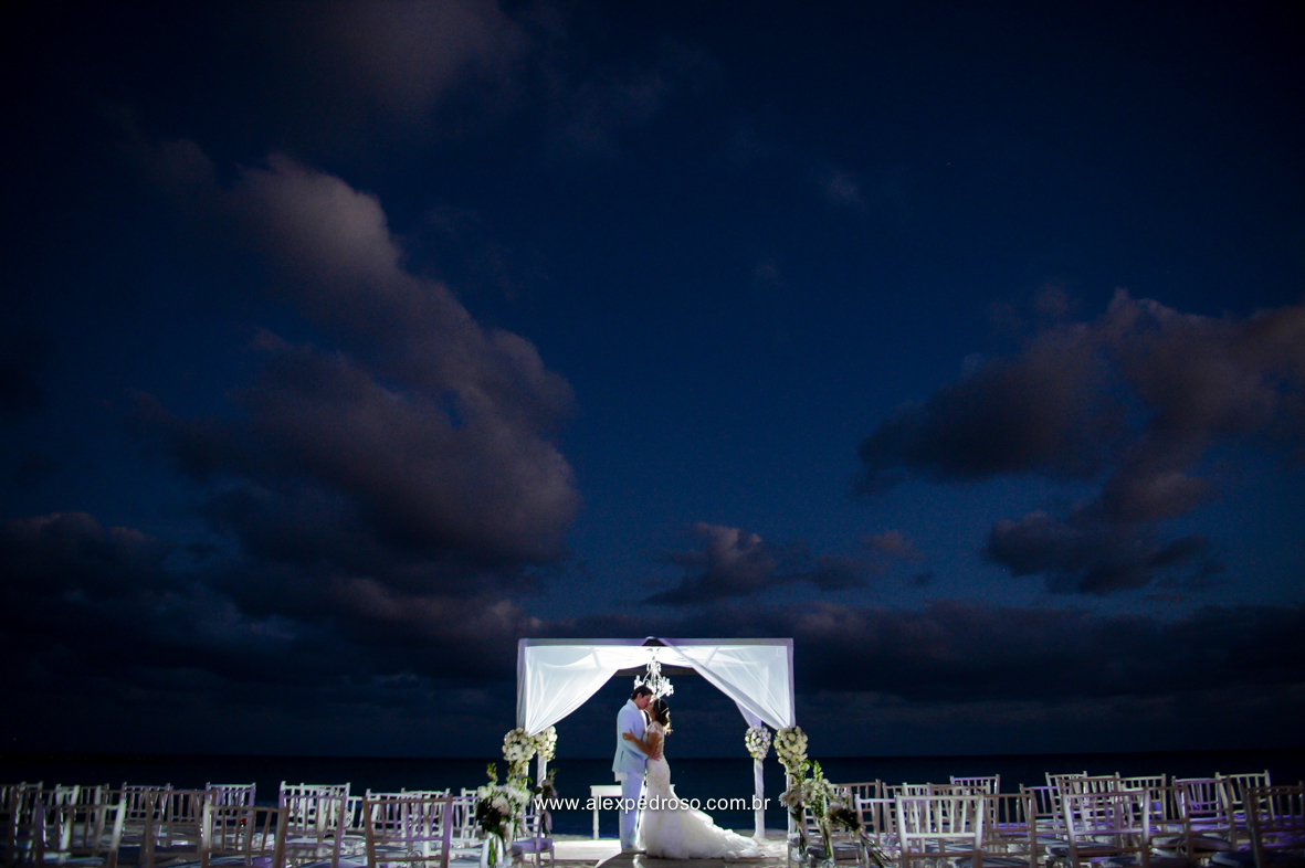 fotos da noiva de branco e o noivo de azul claro com um terno do Ricardo Almeida unidos no altar feito na praia e de fundo o ceu apos o sol se por com a lua de fundo 