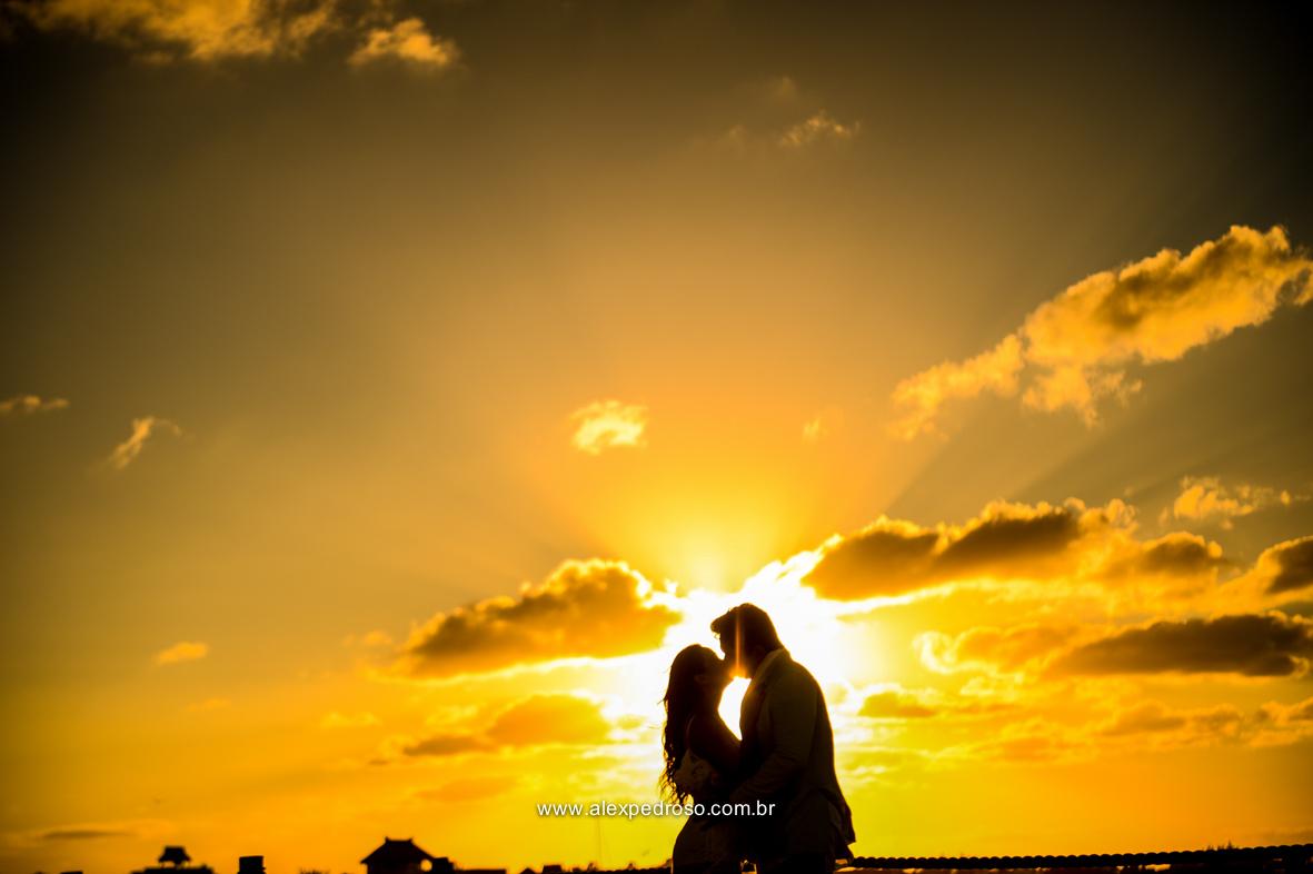 noiva vestindo brando com um vestido mais solto e noivo vestindo terno Azul Clora do Ricardo almeida  bem juntos com o por do sol ao fundo o mar aparecendo no deck no mar do caribe no mexico 