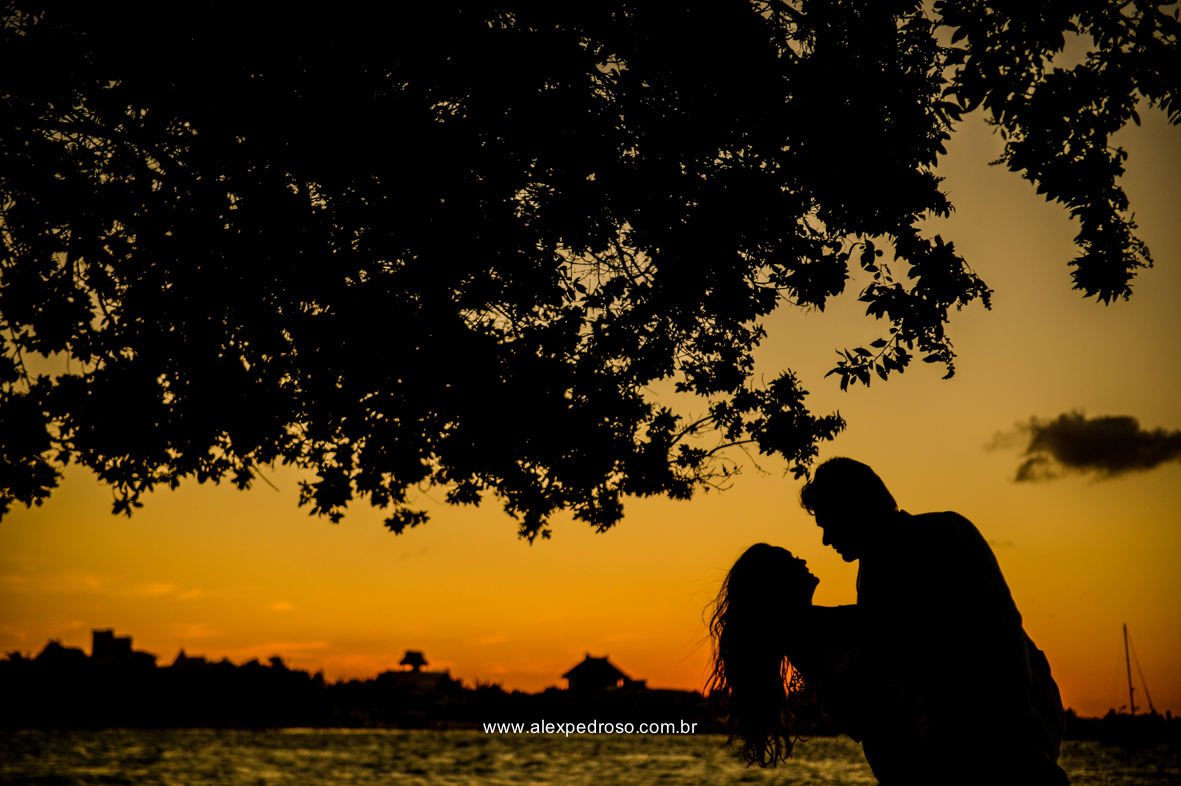 noiva vestindo brando com um vestido mais solto e noivo vestindo terno Azul Clora do Ricardo almeida  bem juntos com o por do sol ao fundo o mar aparecendo no deck no mar do caribe no mexico 