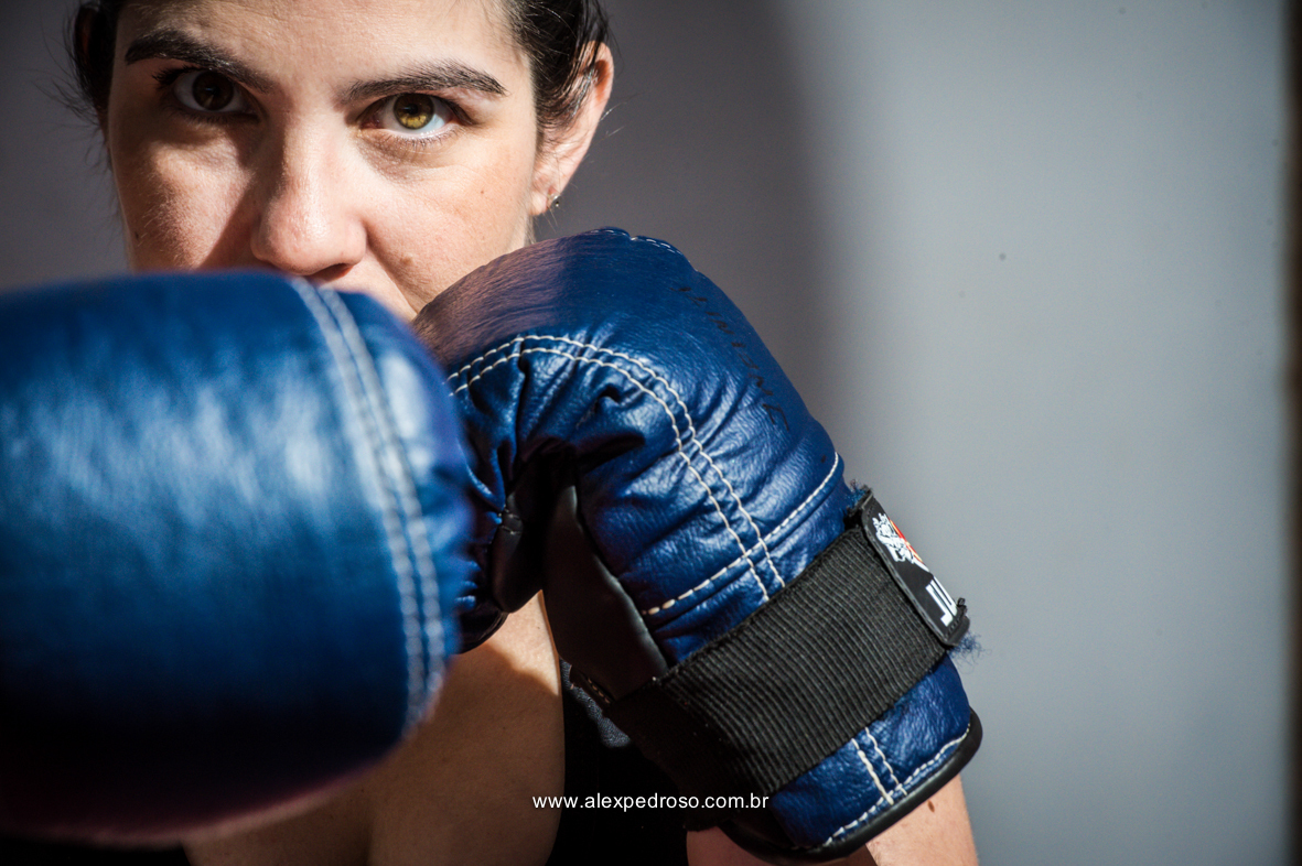Mulher gestante com luvas de boxe azul, com a foto somente pegando o rosto e o olhar