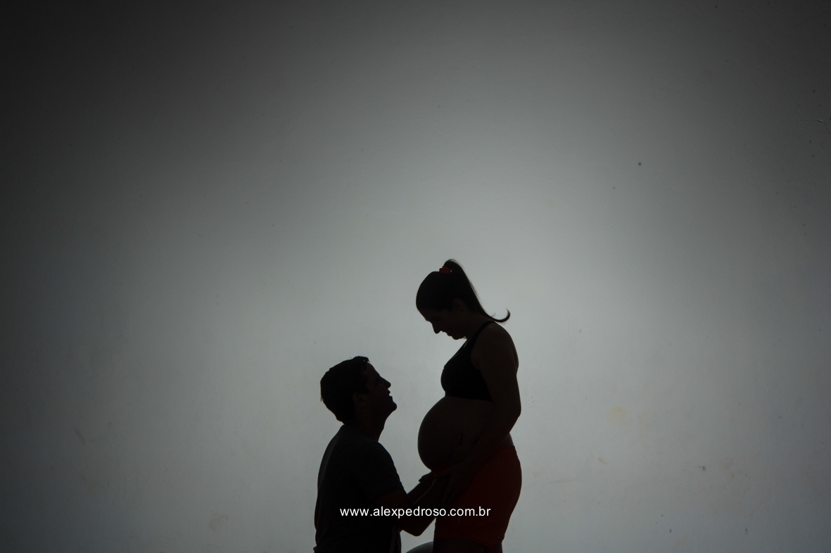 Futuro pai olhando para a mãe gestante, em uma foto preta e branca e a mãe retribuindo o olhar para o pai, os dois com a mão na barriga da gestante