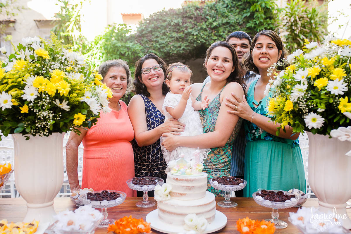 fotografia-de-batizado-de-menina-e-festa-de-um-ano-gruta-nossa-senhora-de-lourdes-tijuca-rio-de-janeiro-decoracao-em-tons-de-amarelo-familia-na-mesa-do-bolo