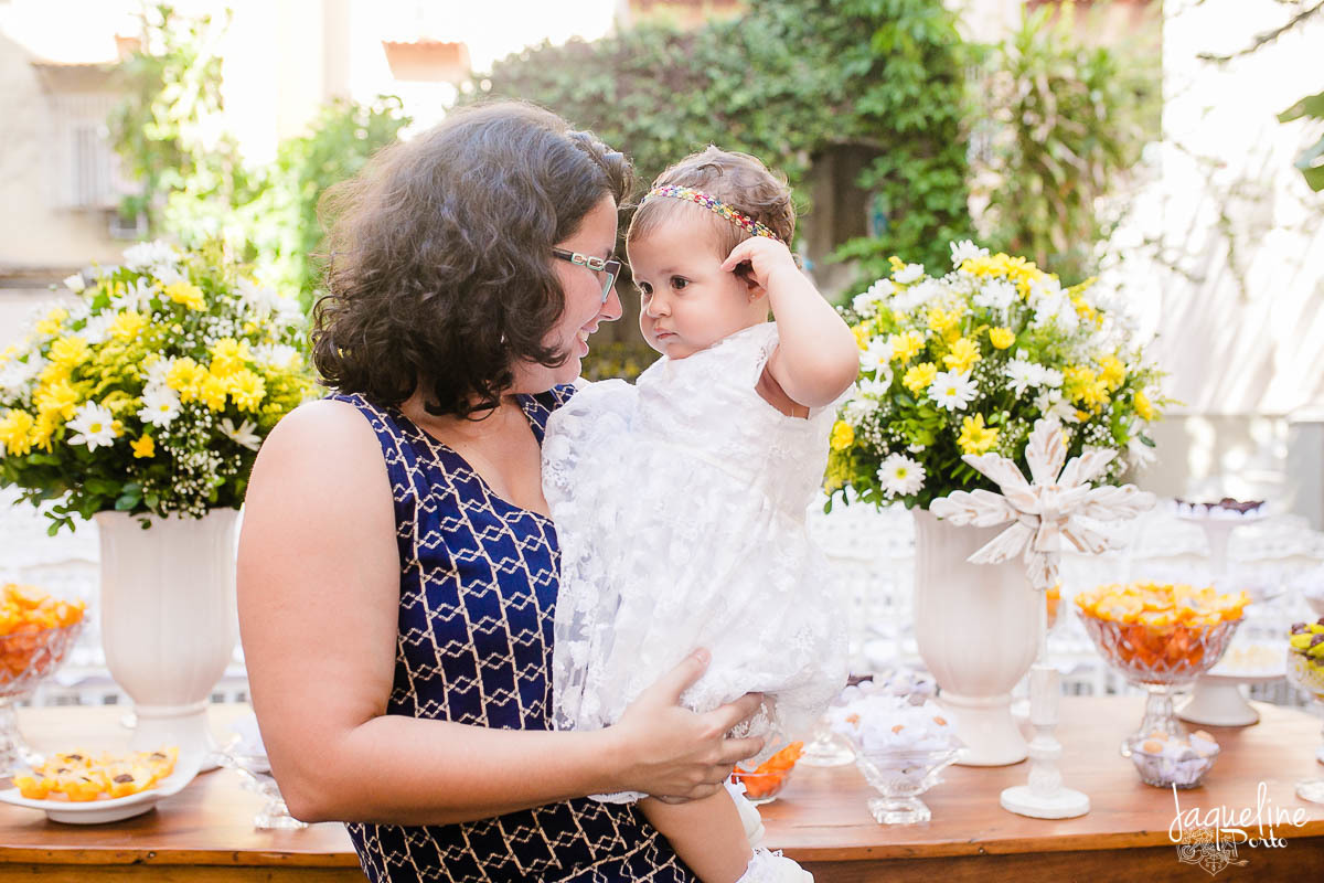 fotografia-de-batizado-de-menina-e-festa-de-um-ano-gruta-nossa-senhora-de-lourdes-tijuca-rio-de-janeiro-decoracao-em-tons-de-amarelo-crianca-e-madrinha-na-mesa-do-bolo